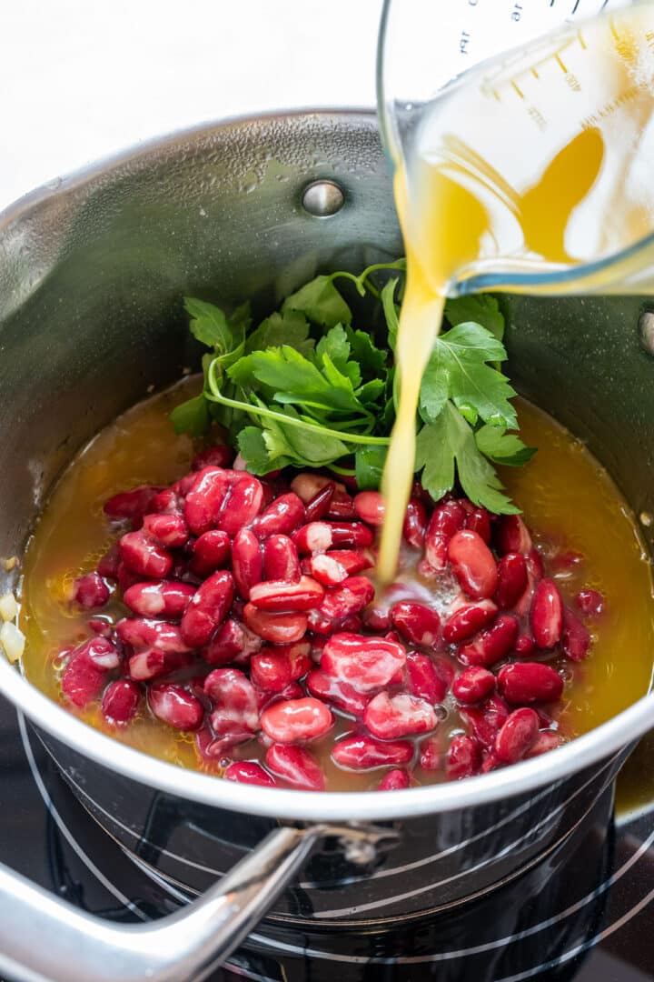 Red kidney beans and vegetable broth added to the pot with parsley.
