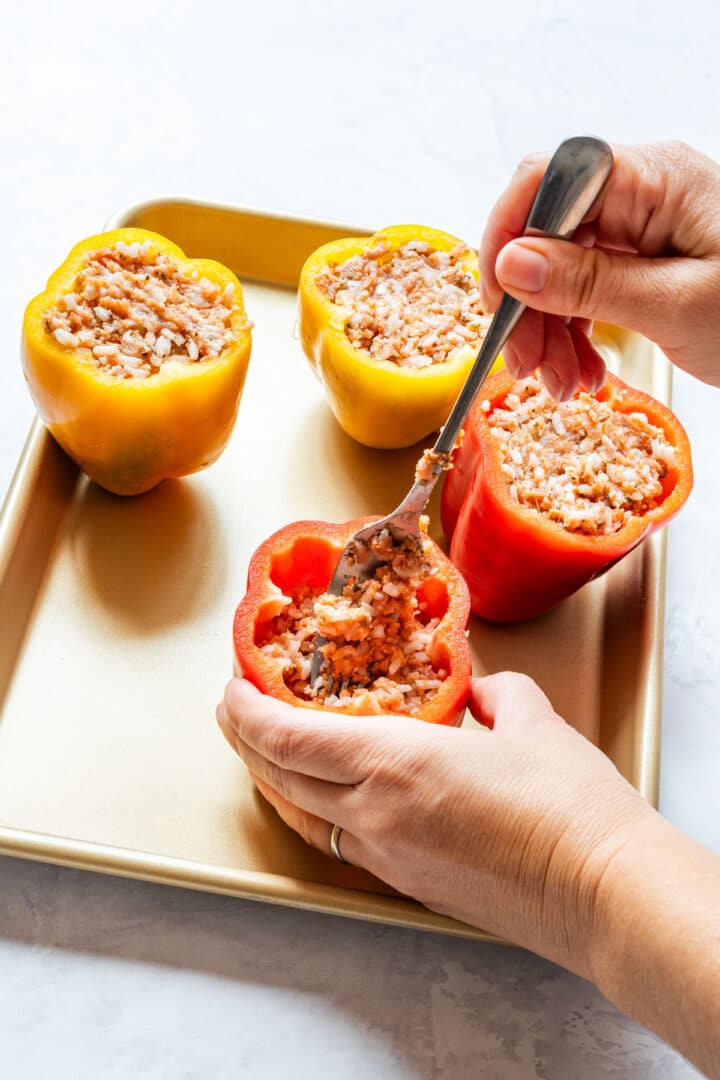 Filling bell peppers with a ground meat and rice mixture.