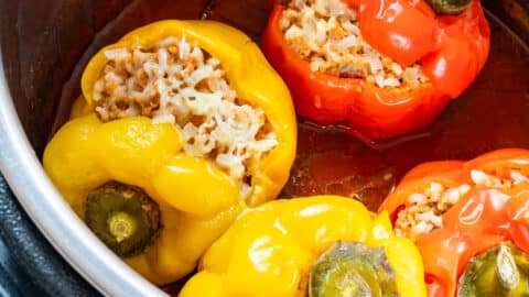 Close-up of stuffed bell peppers in the Instant Pot with tomato sauce and melted cheese.