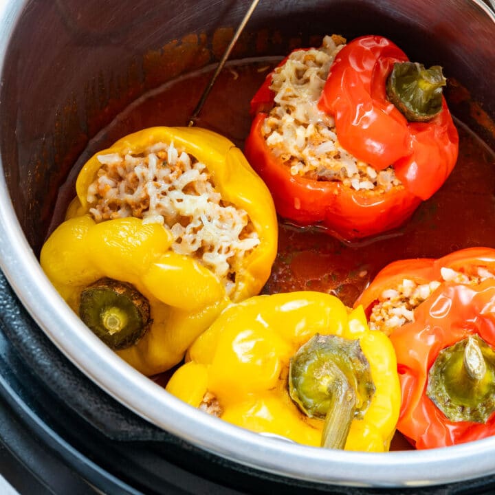 Close-up of stuffed bell peppers in the Instant Pot with tomato sauce and melted cheese.