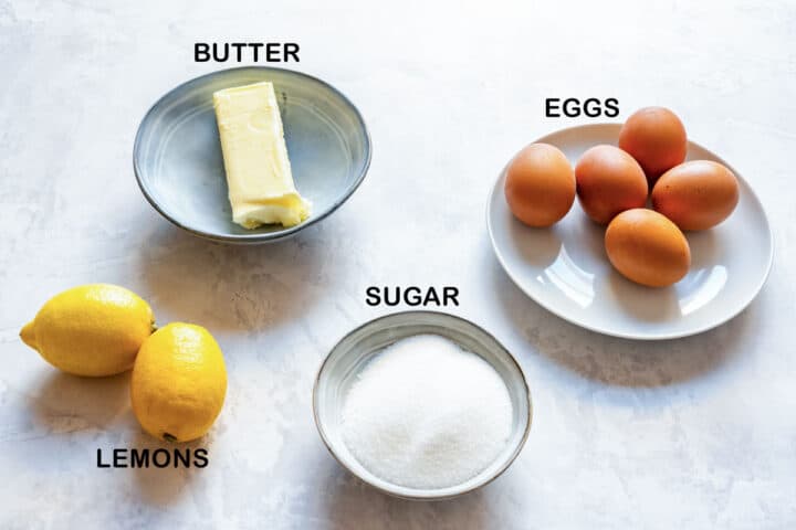 Whole egg lemon curd ingredients: butter, eggs, sugar and lemons on a counter.