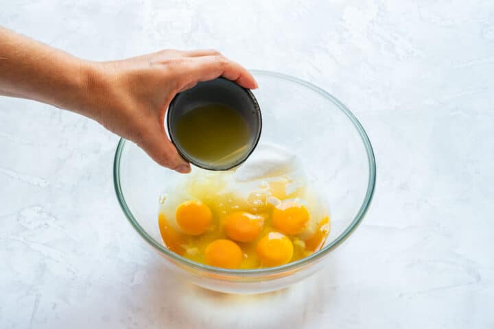 Pouring fresh lemon juice into a bowl with eggs and sugar.
