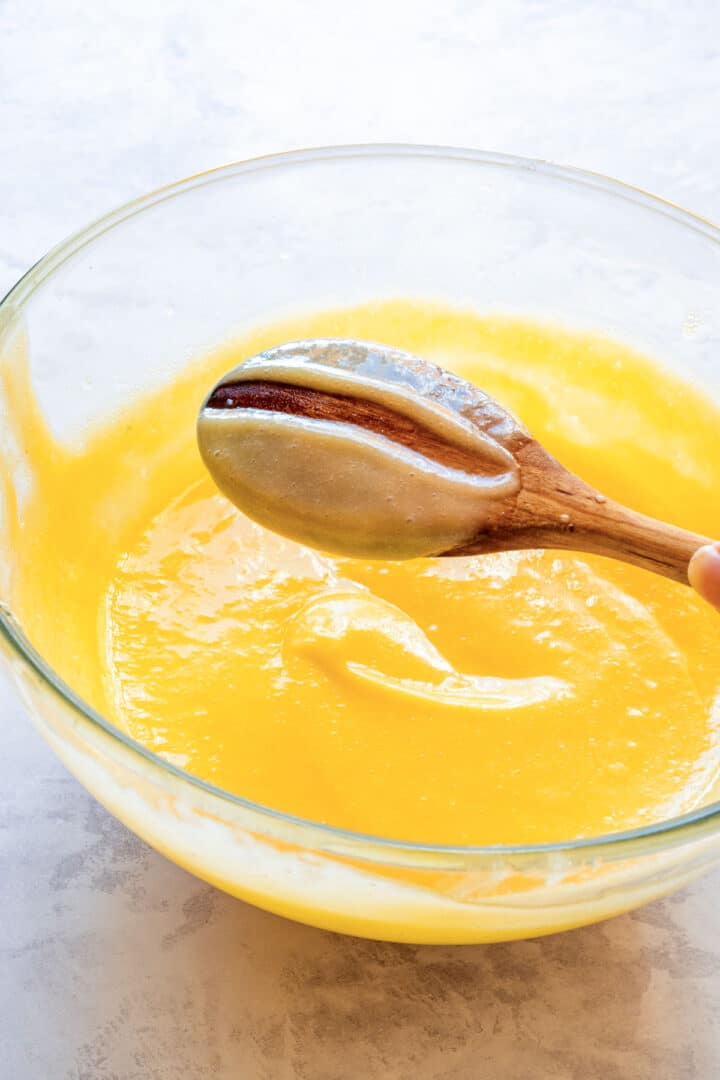 Thickened curd coating the back of a wooden spoon.
