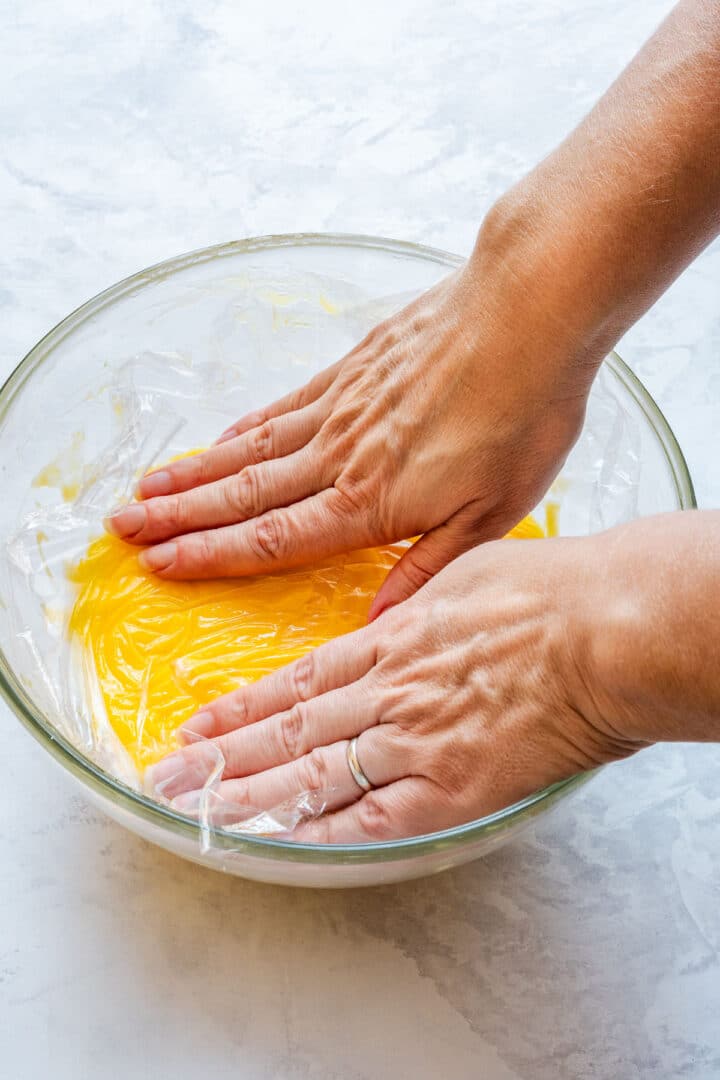 Pressing plastic wrap directly onto the surface to prevent a skin.