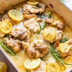 Lemon rosemary chicken thighs with lemon slices and rosemary in a rich lemony sauce, close-up.