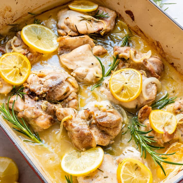 Lemon rosemary chicken thighs with lemon slices and rosemary in a rich lemony sauce, close-up.