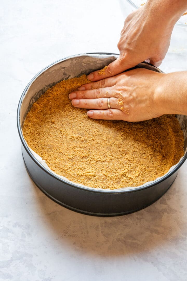 Pressing the crumb mixture up the sides of the pan to form the crust.