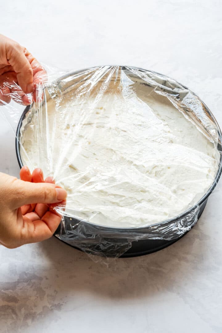 Covering the pie with plastic wrap before chilling.