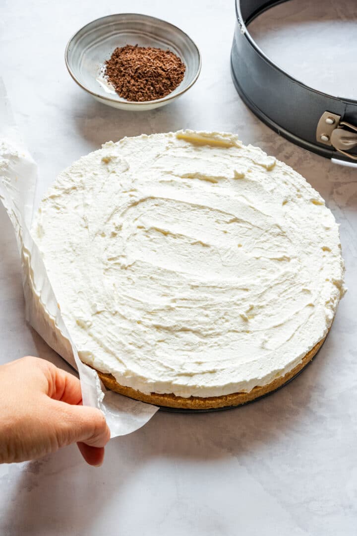 Removing the parchment paper from the chilled pie after releasing the springform pan.