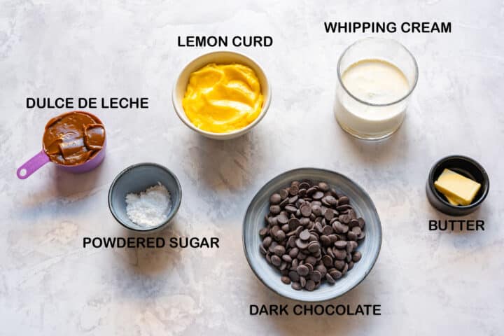 Ingredients for lemon curd dessert cups: dulce de leche, lemon curd, whipping cream, dark chocolate, butter, powdered sugar.