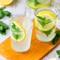 Mint lemonade in two glasses with lemon slices and fresh mint.