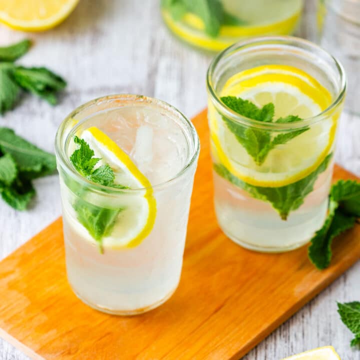 Mint lemonade in two glasses with lemon slices and fresh mint.
