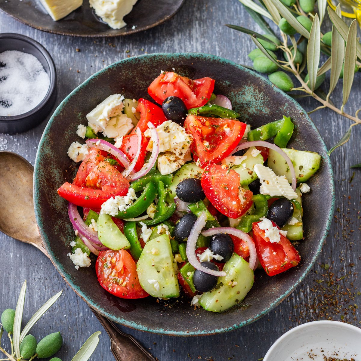 Overhead view of traditional Greek salad with tomatoes, cucumber, green pepper, red onion, black olives and feta in a rustic bowl.