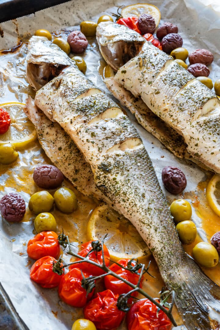 Whole roasted branzino served straight from the pan with cherry tomatoes, olives, lemon and dried dill for an easy Mediterranean fish dinner.