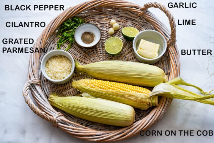 Labeled ingredients for garlic Parmesan corn: corn on the cob, butter, grated Parmesan, garlic, cilantro, lime and black pepper.