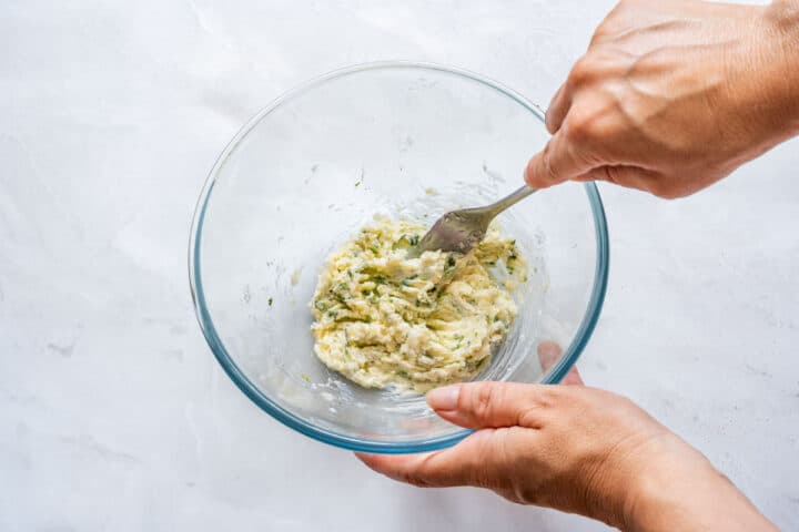 Softened butter, grated Parmesan, garlic and chopped cilantro mixed together in a glass bowl with a fork.