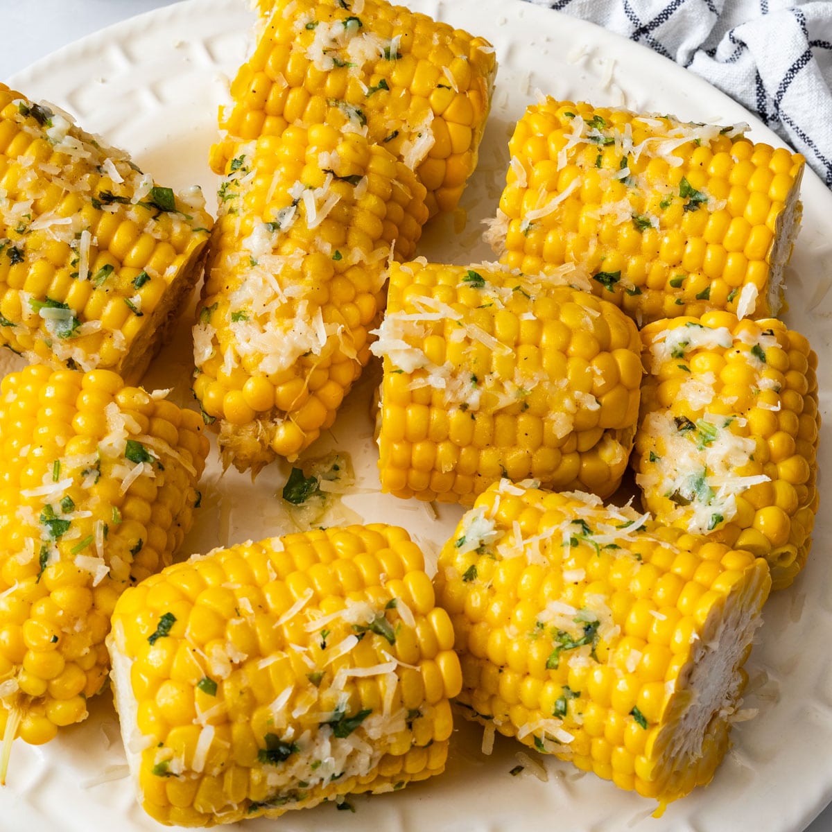 Close-up of corn on the cob pieces coated with garlic Parmesan butter and cilantro.