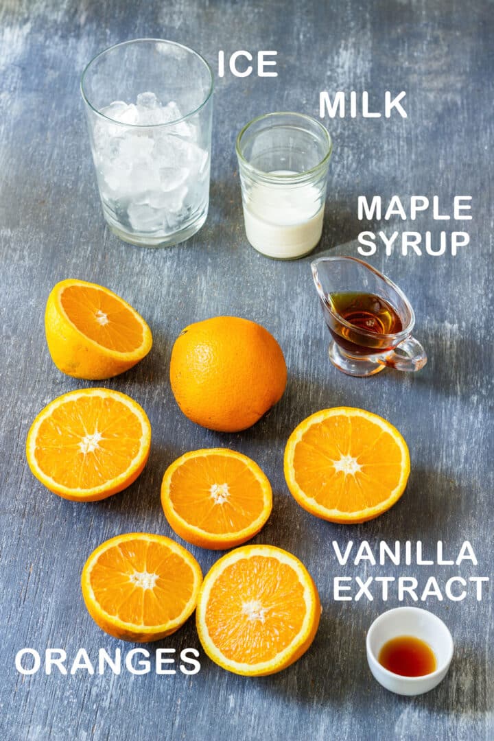 Ingredients for Orange Julius: halved oranges, ice, milk, maple syrup and vanilla extract.