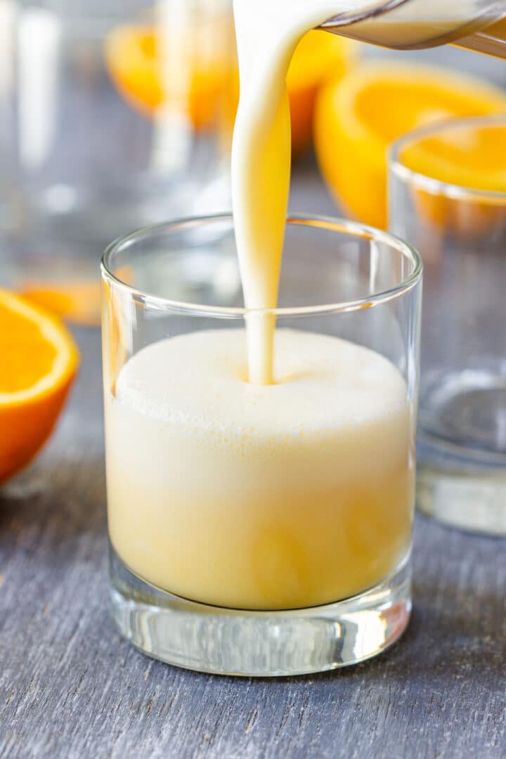 Frothy Orange Julius being poured into a short glass.