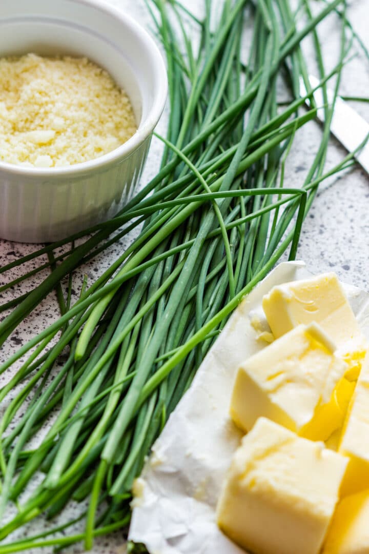 The ingredients for chive butter: grated Parmesan, fresh chives and cubed butter.