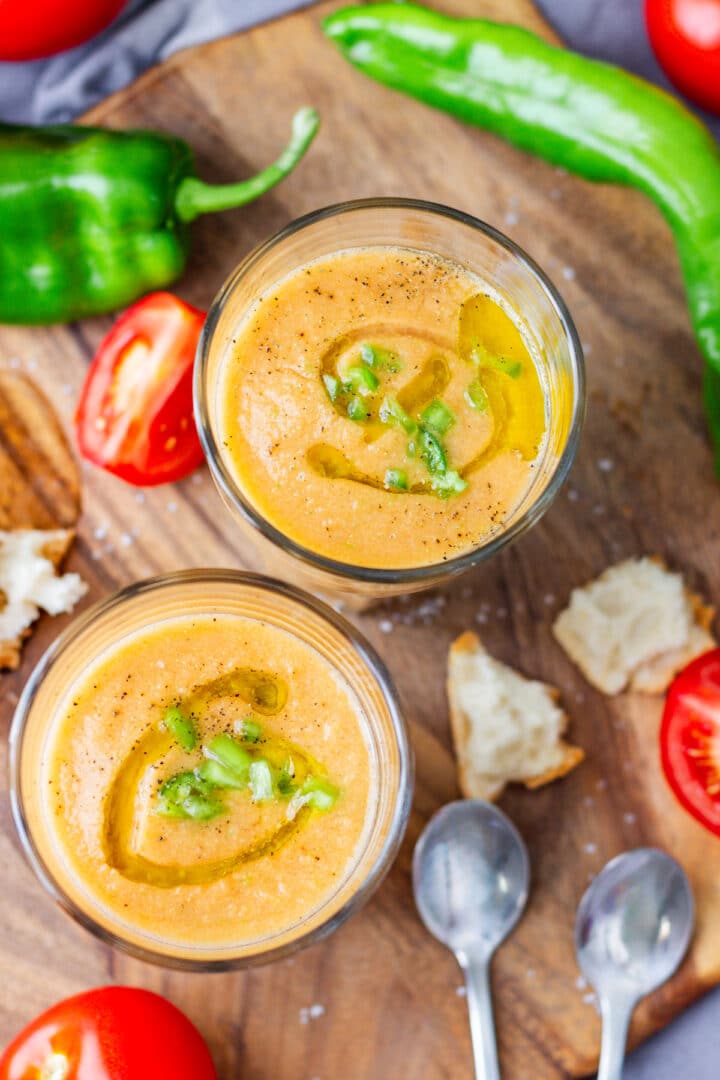 Close overhead view of gazpacho drizzled with olive oil and topped with black pepper and chopped green pepper.