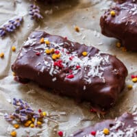 A single homemade Bounty bar on baking parchment, finished with shredded coconut, bee pollen and freeze-dried berries.