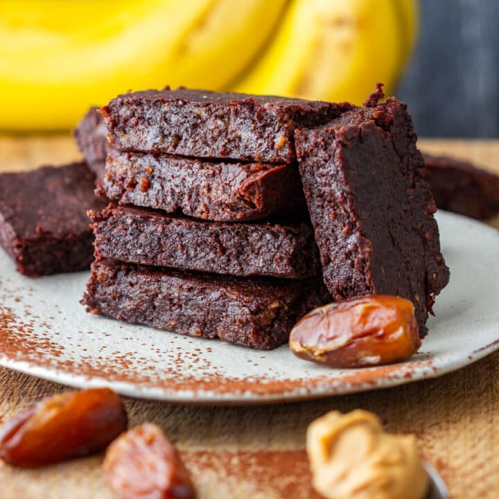 Fudgy brownies made with dates, banana and peanut butter stacked on a plate.