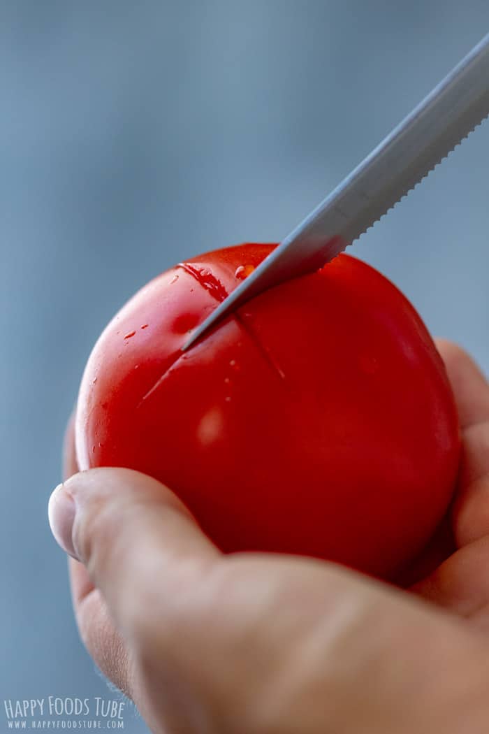Cutting a small X into the bottom of a tomato before blanching it to loosen the skin.
