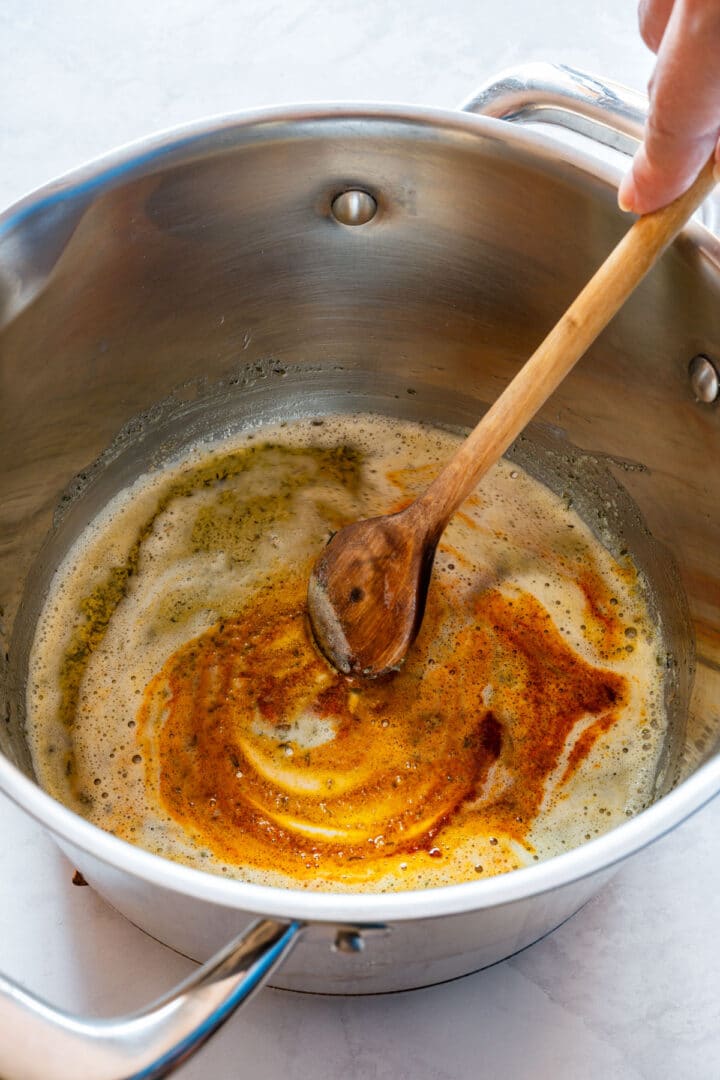Dried thyme, sage and paprika mixed into melted butter in a saucepan.
