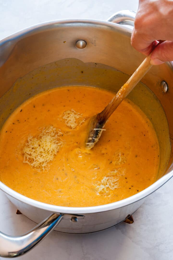 Grated cheddar being added to the smooth sweet potato and milk sauce.