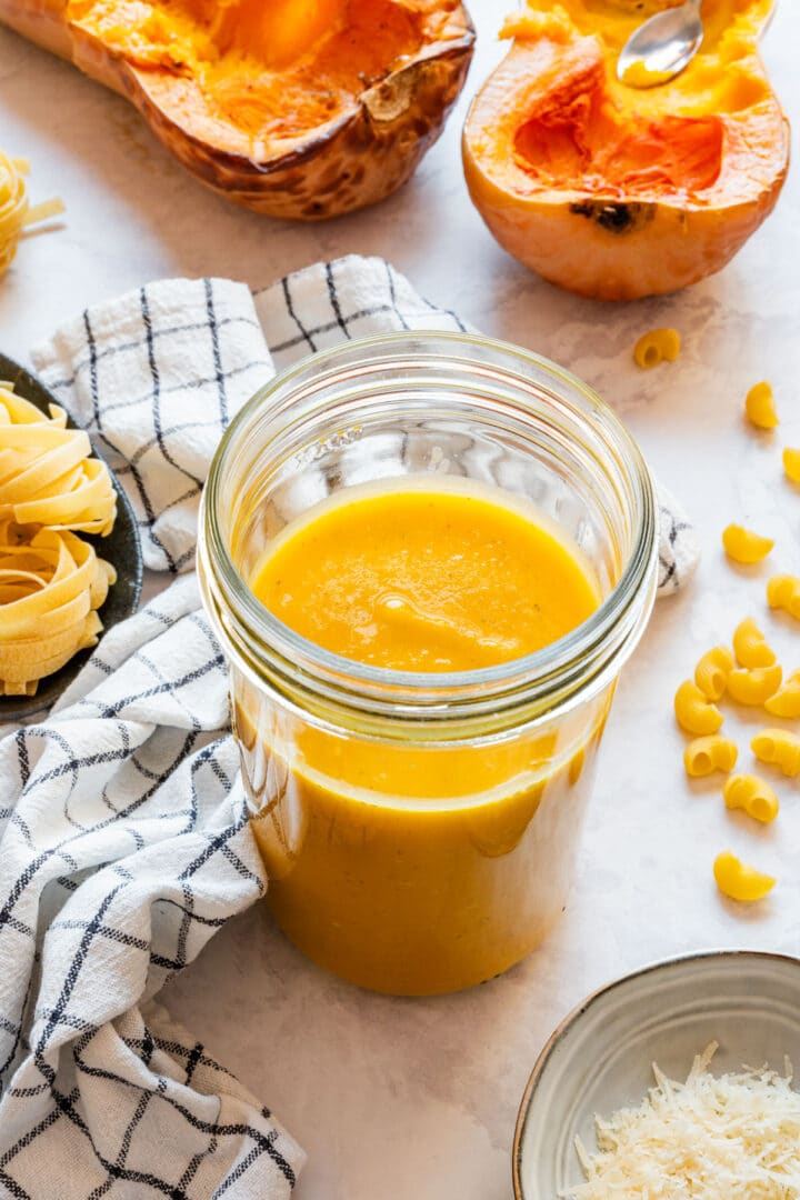 A tall glass jar filled with smooth, thick butternut squash sauce.