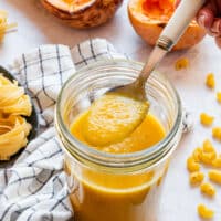 Spoonful of smooth, thick roasted butternut squash sauce held over a full jar.