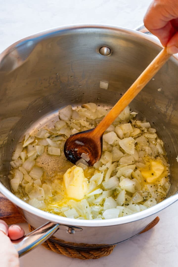 Onion, garlic and dried sage sautéing with butter and olive oil in a pot.