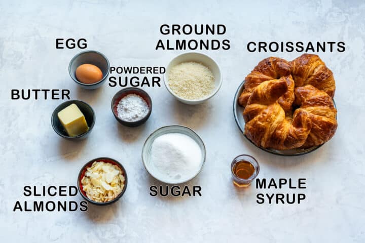 Labeled ingredients for almond croissants: croissants, egg, butter, sugar, powdered sugar, ground almonds, sliced almonds and maple syrup.