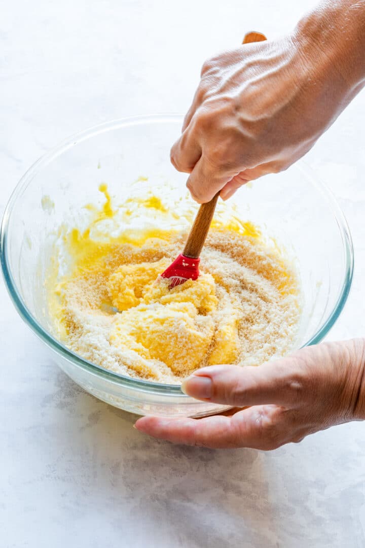 Ground almonds being stirred into the butter and egg mixture with a spatula.