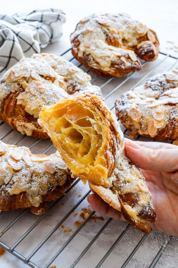 A croissant held open to show its flaky layers and soft almond filling.